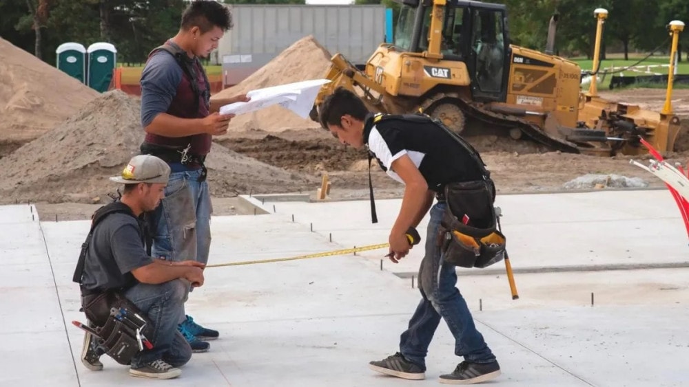 Three men working on a house construction site.