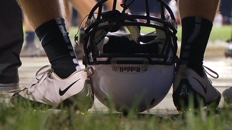 Image of football player's cleat clad feet with helmet.