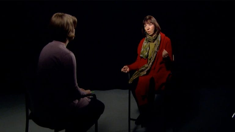 Two women talking as they sit facing each other on a studio set.