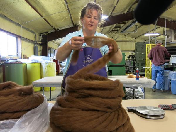 Image of yarn maker handling wool during yarn-making process