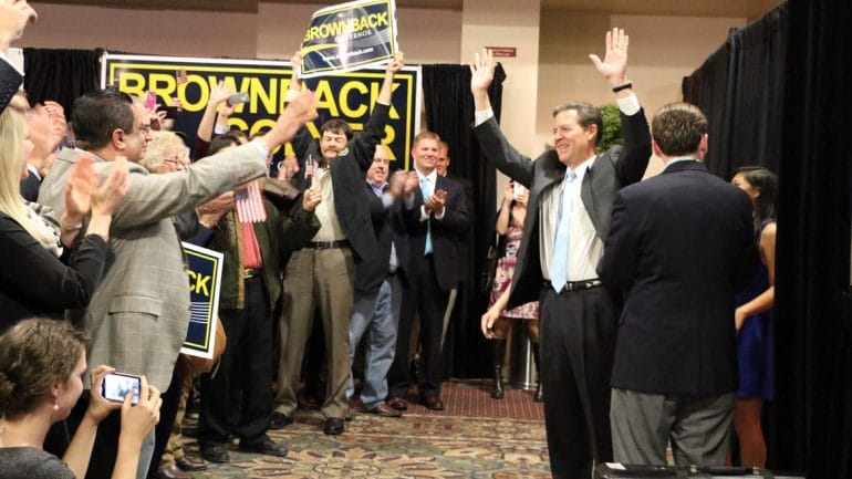 Governor Sam Brownback raising arms in front of crowd