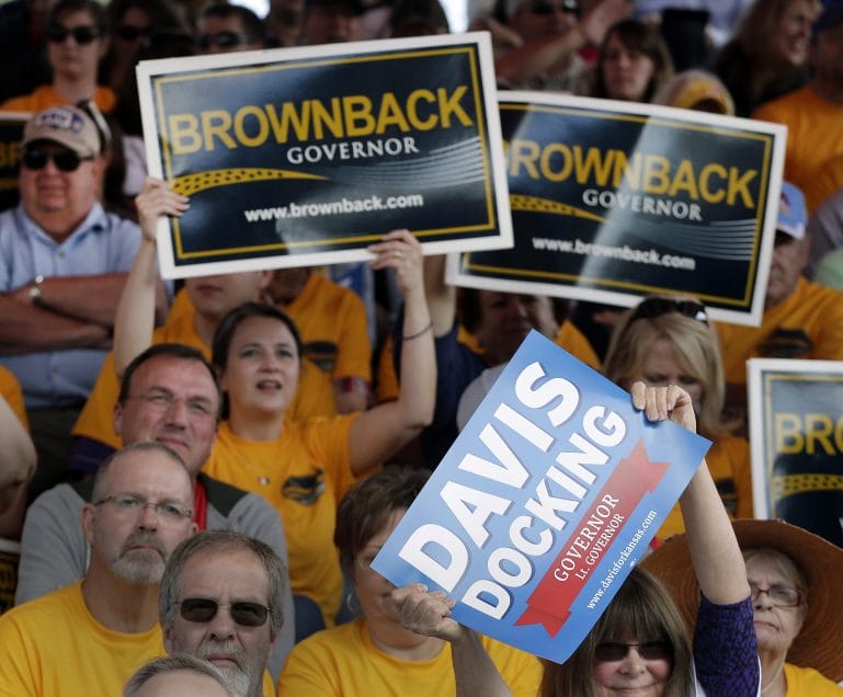 Photo of crowd holding Brownback and Davis/Docking signs at debate