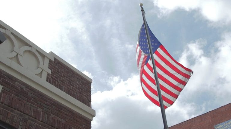 Image of American flag waving in front of brick building