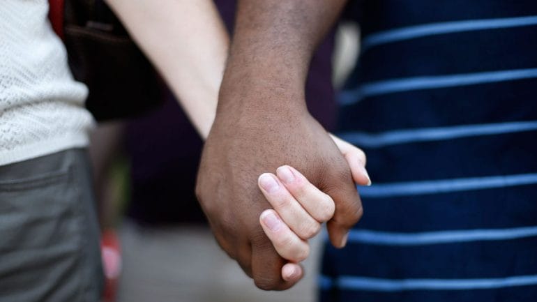 a white woman and black man hold hands