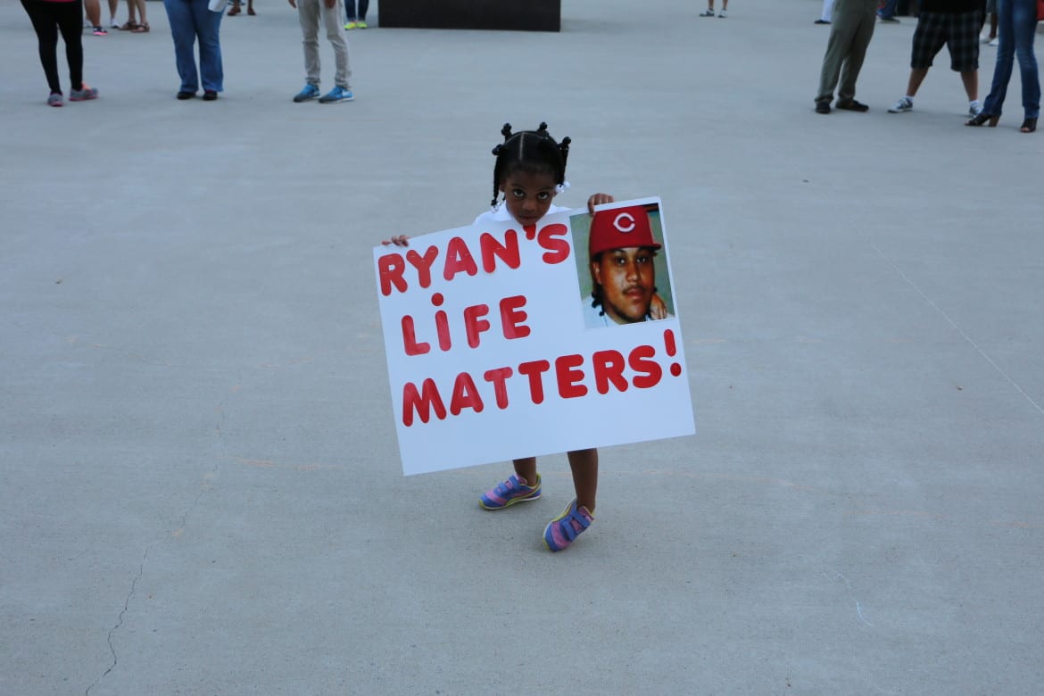 Neriha Stokes, the daughter of Ryan Stokes holding sign at vigil that says Ryan's Life Matters