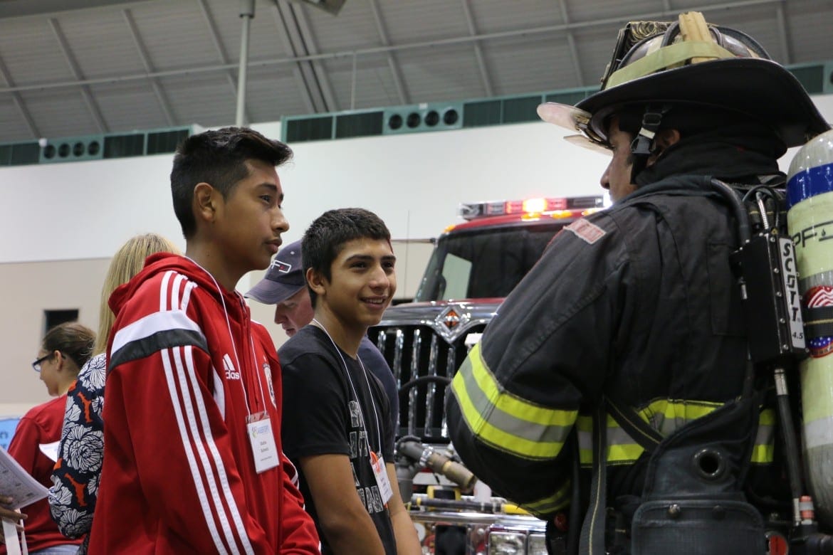 Jesus Isidor, 14, left, and Samuel Ortiz, 15, a freshman and sophomore, respectively, at Olathe North High School, got some information from Overland Park firefighter Brian Minick, who piqued their interest by telling them the department pays bonuses for personnel who are fluent in Spanish.