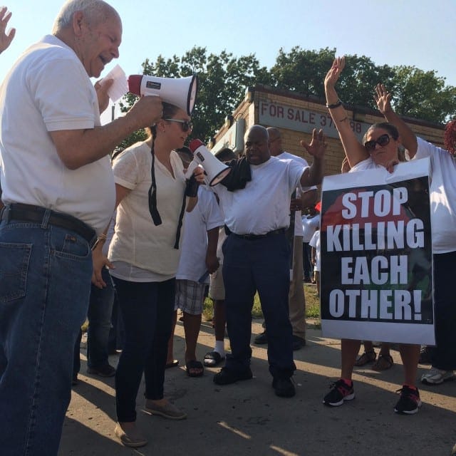 Pastor Francisco Lara (left) delivers a impassioned speech at an anti-violence rally in Kansas City, Kansas while his daughter, Raquel, translates his Spanish to English. (Photo: Alex Smith | Heartland Health Monitor)