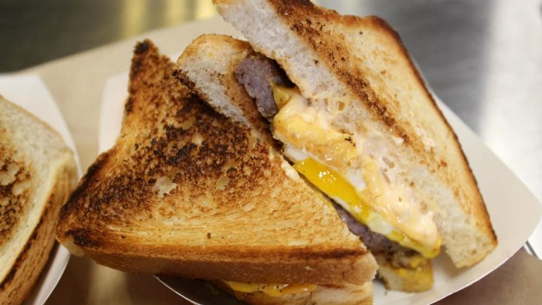 Photo of toasted sandwich with egg, cheese and sausage.