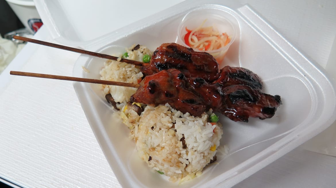 A pair of pork skewers over rice.