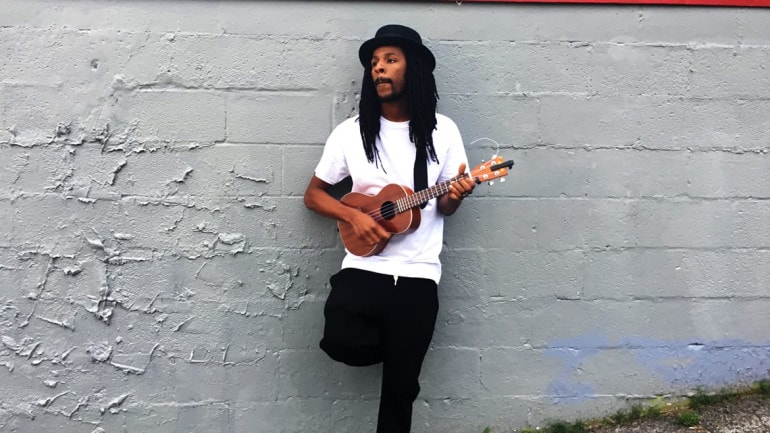 Man standing against wall with ukulele