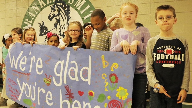 Franklin Smith kids welcoming visitors with a banner