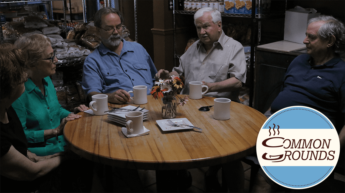 A group of five people seated over coffee at a restaurant