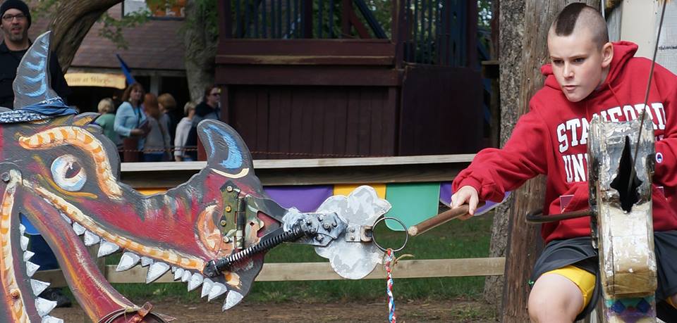 A festival-goer plays with a stationary dragon.