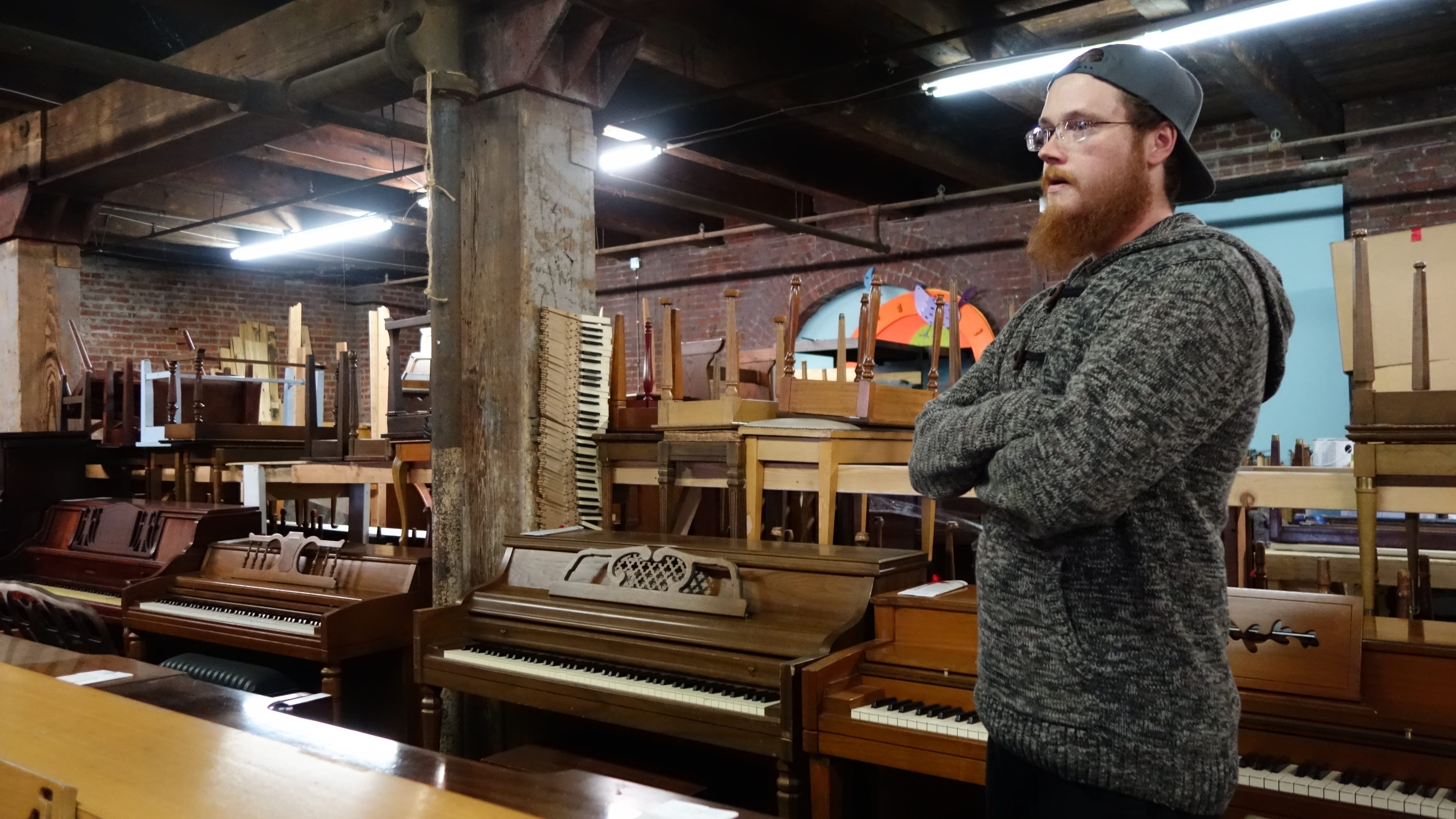 A man standing near pianos.