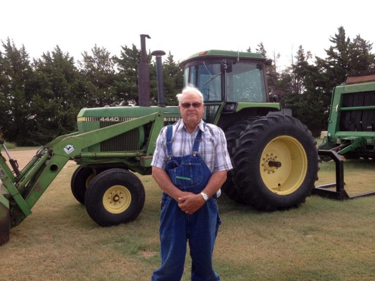 A man standing in front of his farm equipment.