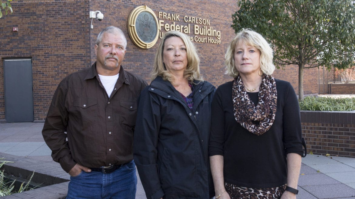 One man and two women standing outside a court house.