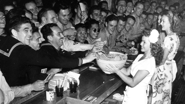 A young actress serves cookies to WWII Servicemen