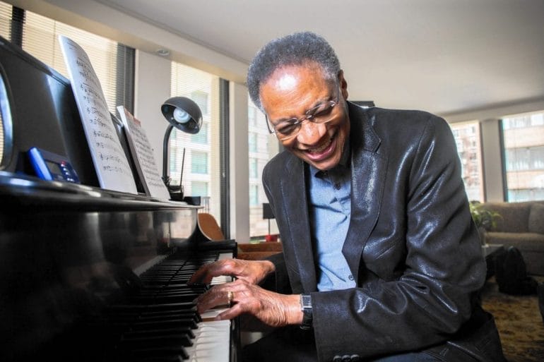 Ramsey Lewis plays the piano laughing.