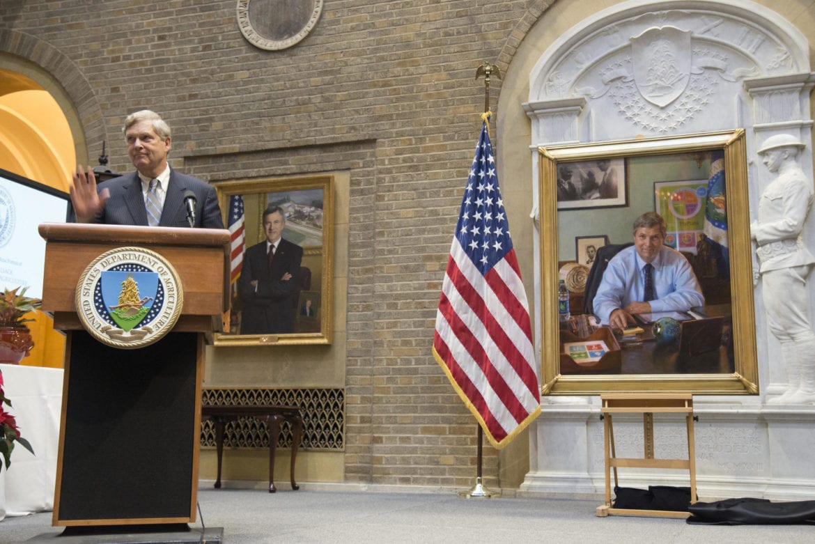 A man in a room with a portrait of himself.