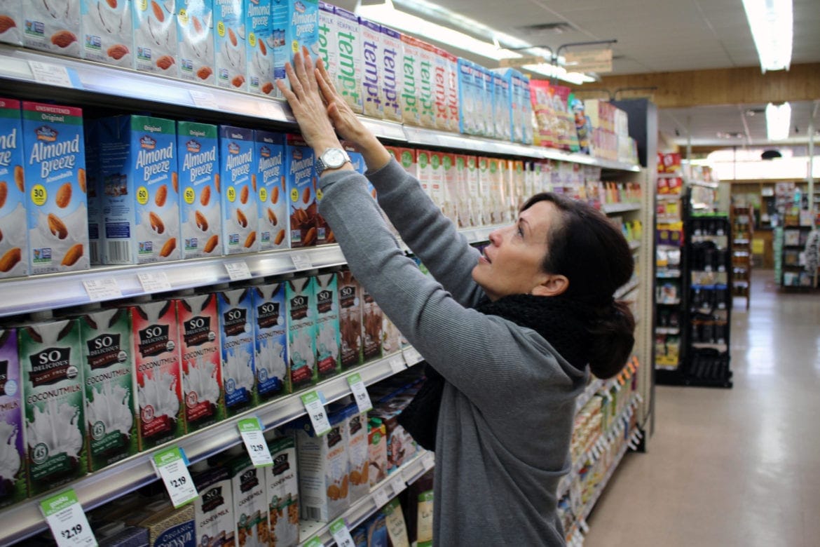 A woman reaching for non-dairy milk.