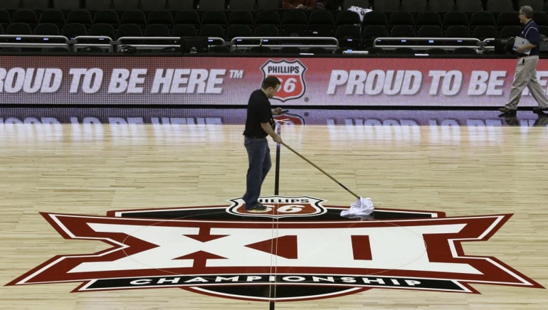 A worker cleans a basketball court floor