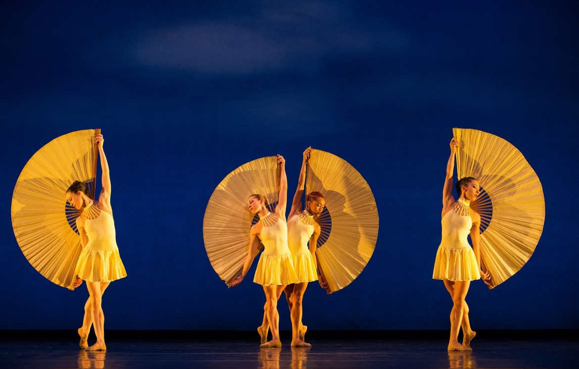 Four women in yellow costume posing against a blue backdrop.