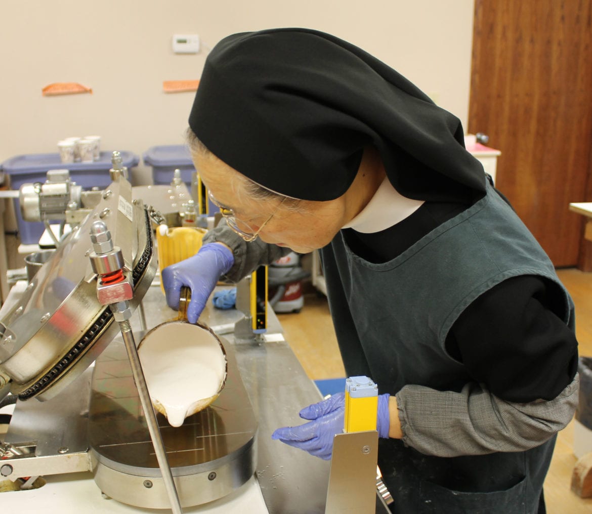 Sister Marie Jona pours low-gluten altar bread batter onto a baker.