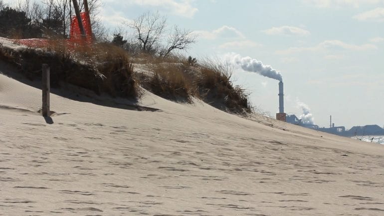 A beach with a visible smokestack in the background