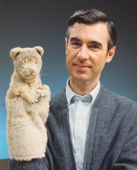 Fred Rogers wearing a tiger puppet on his hand.