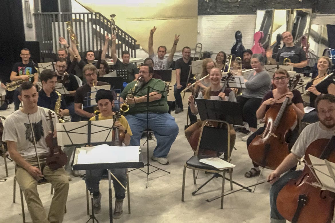 A crowd of musicians playing orchestral instruments.