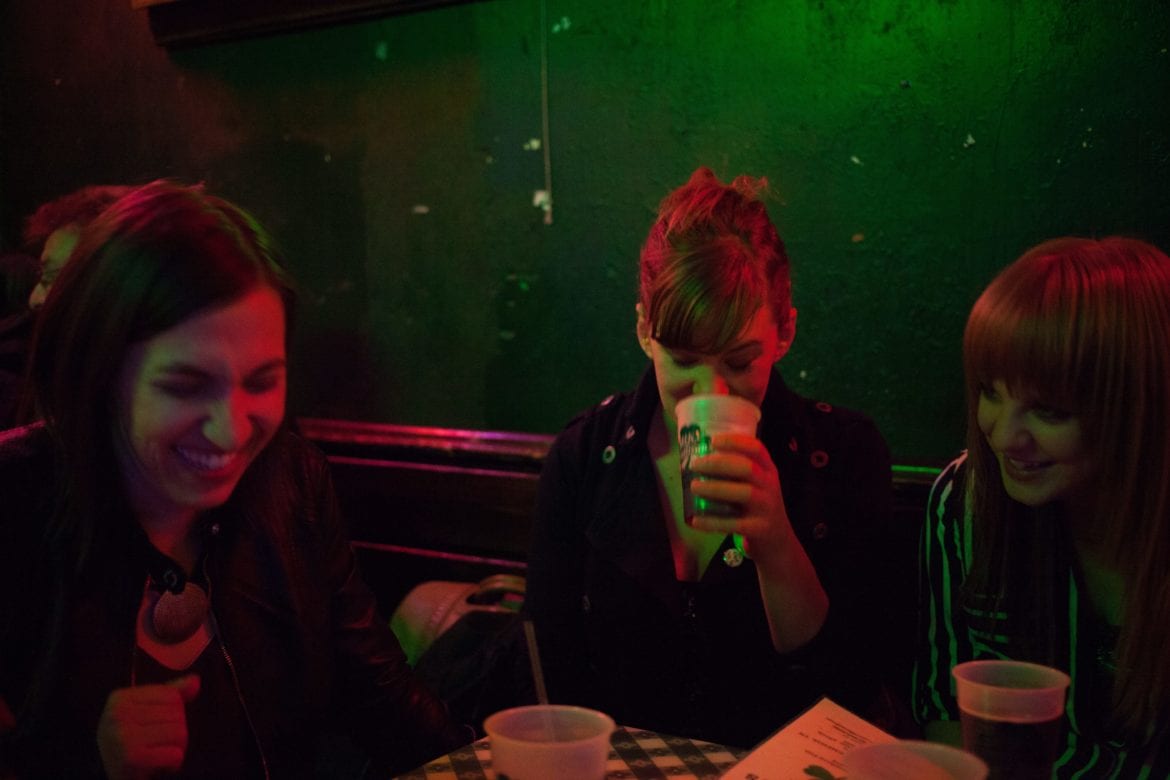 Three women in a dimly lit room siting at at table.