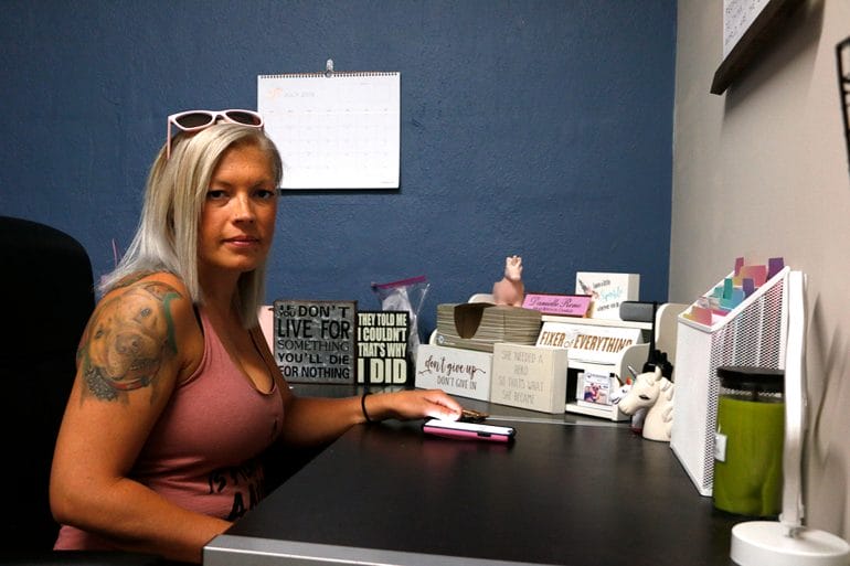 Danielle Reno sits at a desk in her office