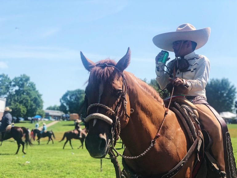 A boy on a horse with a cowboy hat clutches the saddle and sips a Sprite while taking a break during the Latino Arts Festival on Sept. 7. (Vicky Diaz-Camacho | Flatland) 
