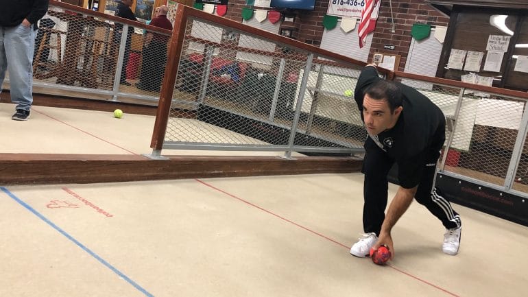 A man readies to roll his bocce ball.