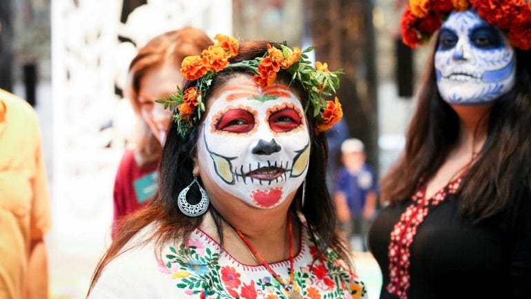 A woman poses in full calavera face paint.