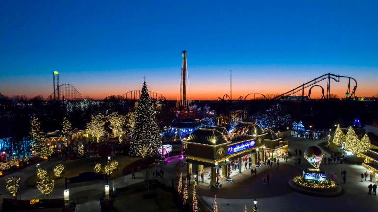 An aerial shot of Worlds of Fun lit up with Christmas lights at sunset.