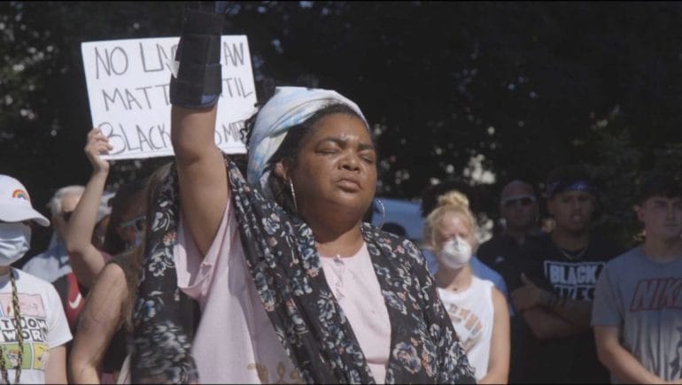 A protester raises her fist during Reggie Palmer's speech at a "Black Lives Matter" protest in Marshall, Missouri on Sunday, June 7, 2020.