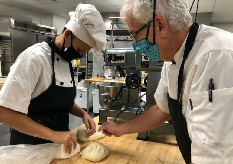 Culinary instructor Bob Brassard offers some hands-on baking instruction to Destany Moore.