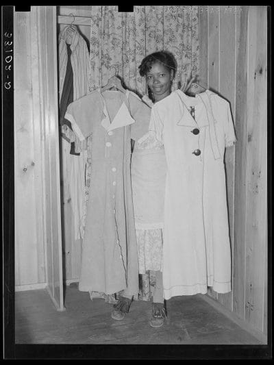 The wife of Farm Security Agent client holding dresses she made from flour sacks in Marshall, Texas, 1939.