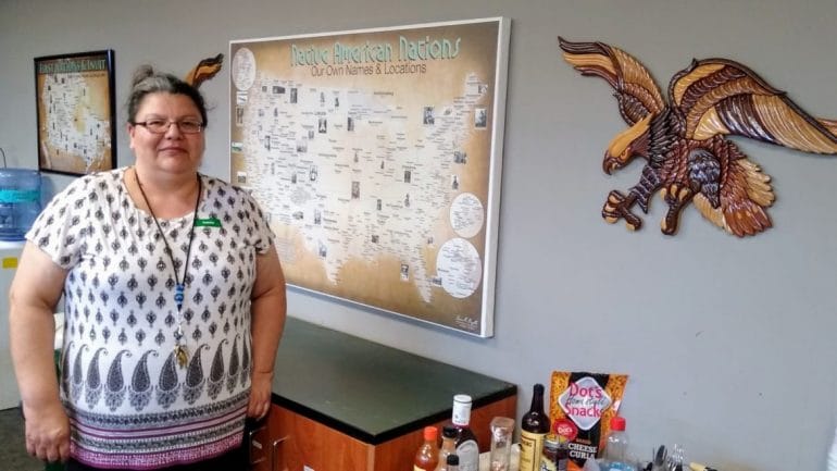 Gaylene Crowser, a member of the Standing Rock Sioux tribe, has been executive director of the Kansas City Indian Center for nine years. Behind her at the center is a map showing the location of some of the more than 500 federally recognized tribes of Indigenous people.