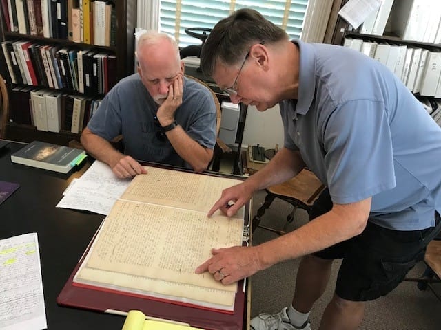 tephen Haymes, retired Clay County Circuit Court clerk (left) and Tony Meyers, Clay County Archives & Historical Library president, examine a court ledger book which contains the 1841 conclusion of a formal court partitioning of four enslaved people among several owners.