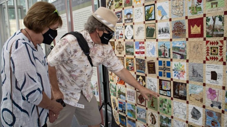 Steve and Calene Cooper identify blocks and stories shown in the Missouri Bicentennial Quilt.