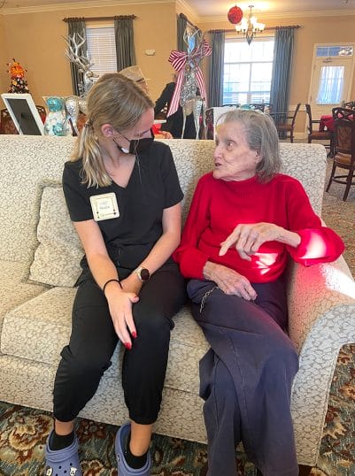 Felicia Honey, left, sits with one of the residents she cares for at Benton House of Lenexa.