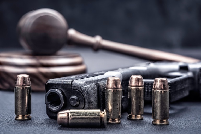 Bullets lined up in front of a gun are propped in front of a gavel. This is illustrative of the Flatland Show's next topic: gun and safety. This month, the curiousKC and Flatland team discuss how to address gun violence in Kansas City. What questions about gun violence do you have?