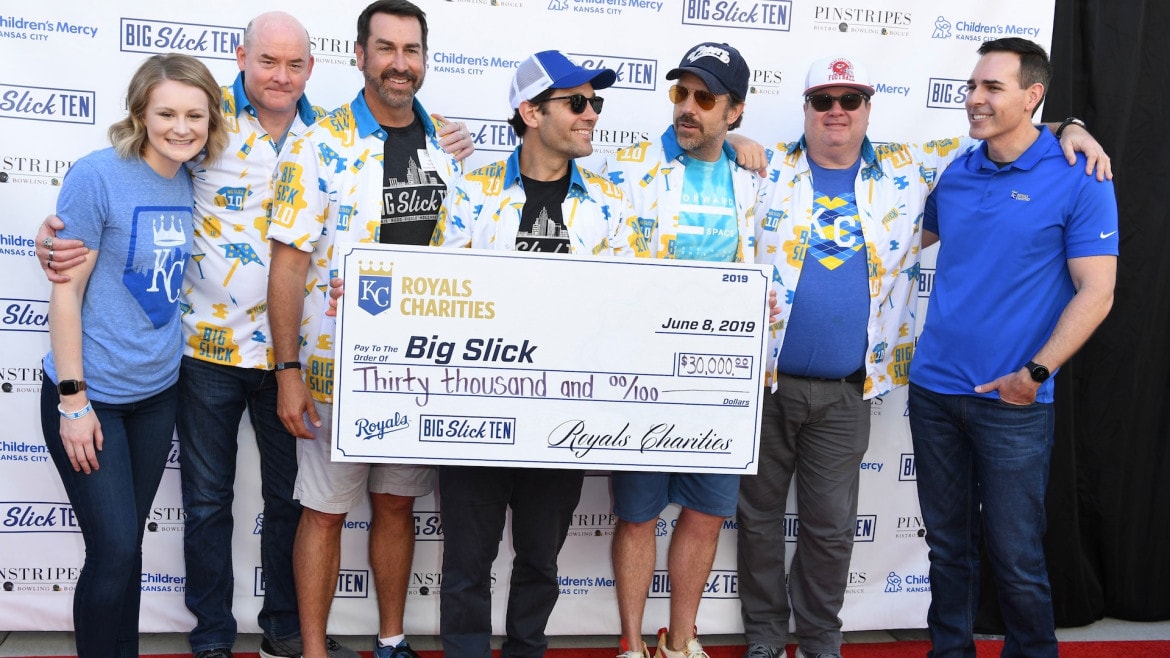 David Koechner, Rob Riggle, Paul Rudd, Jason Sudeikis, and Eric Stonestreet pose with a large check at a past Big Slick Weekend.