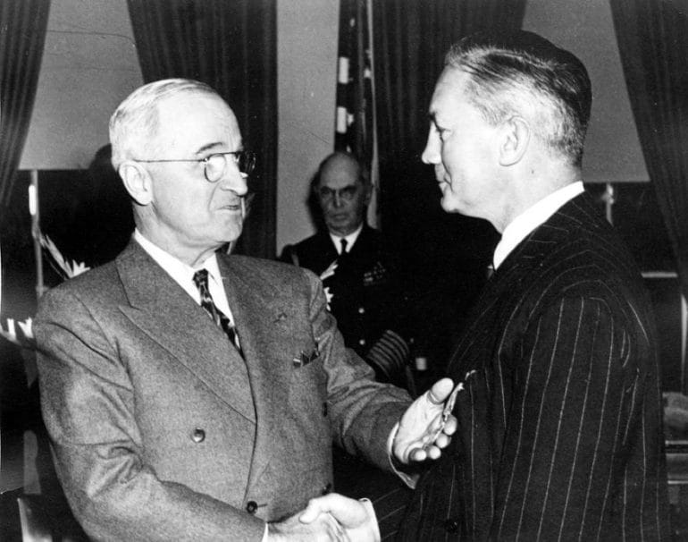 President Harry Truman shaking the hand of Secretary of Defense James Forrestal.
