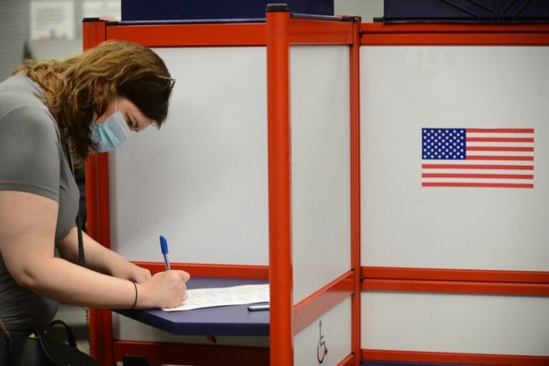 Women in voting a booth.