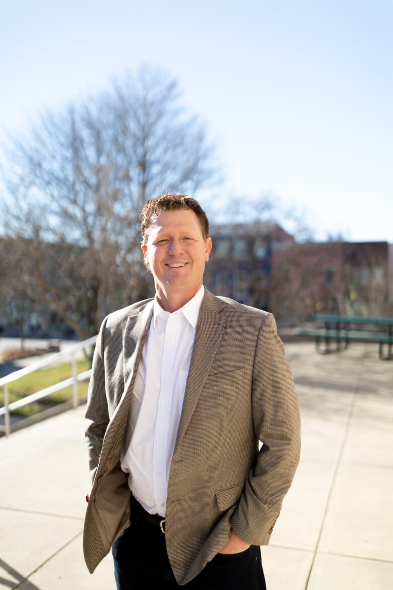 man in suit jacket smiles at camera