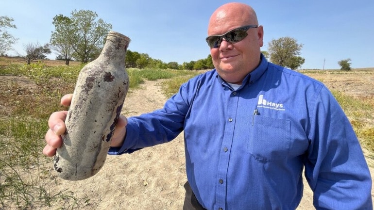 Jeff Crispin, Hays water director, picks up an old bottle from the dry river bed where the Smoky Hill River usually runs. The city's primary water wells sit long the banks of this river nearby.