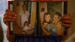 A photo album held by an eight year old's hands, displaying photos of her grandmother and great-grandmother. At the time, she and her parents were living in Puerto Rico. They moved to Kansas after hurricane Maria. ( Ji Stribling | Flatland)